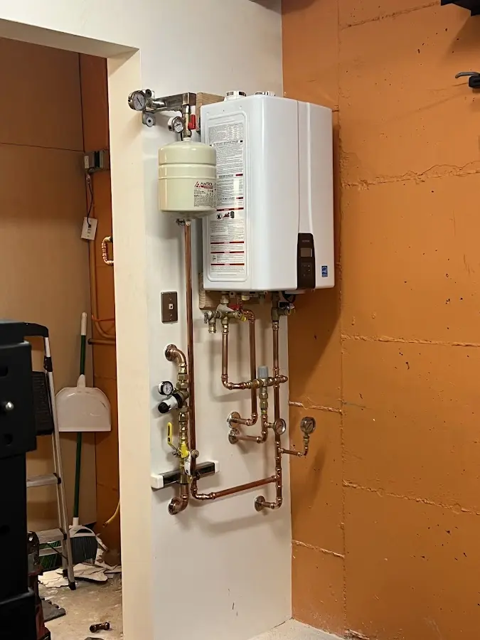 Plumbing technician inspecting water heater connections in Tonawanda
